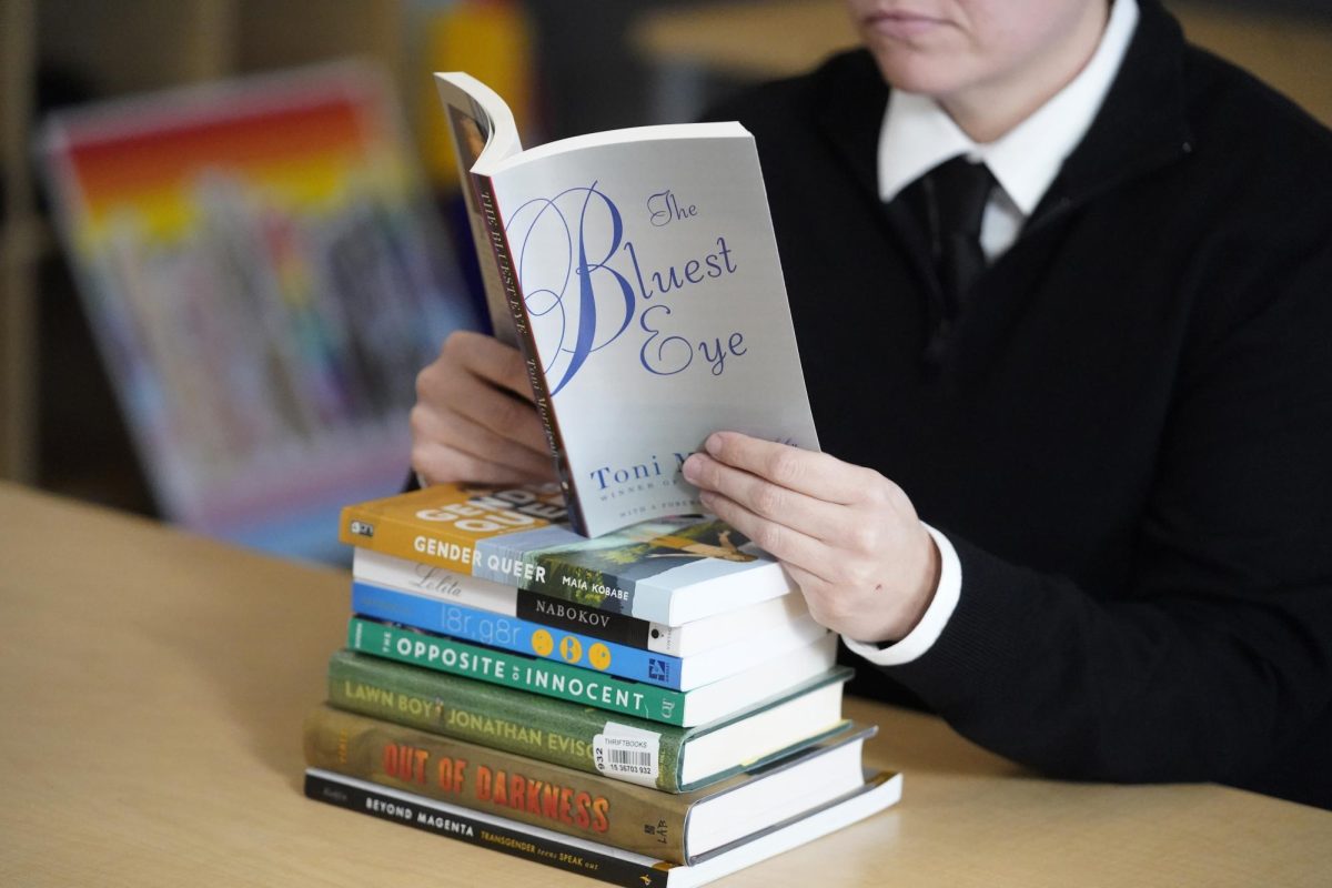 Amanda Darrow, director of youth, family and education programs at the Utah Pride Center, poses with books, including "The Bluest Eye," by Toni Morrison, that have been the subject of complaints from parents, on Dec. 16, 2021, in Salt Lake City. Publisher Penguin Random House and PEN America sued a Florida school district Wednesday, May 17, 2023, over its removal of books about race and LGBTQ+ identities, the latest opposition to a policy central to Gov. Ron DeSantis’ agenda as he prepares to run for president. Among the removed books are “The Bluest Eye” by Toni Morrison, “The Perks of Being a Wallflower” by Stephen Chbosky, “The Nowhere Girls” by Amy Reed and “Lucky” by Alice Sebold. 