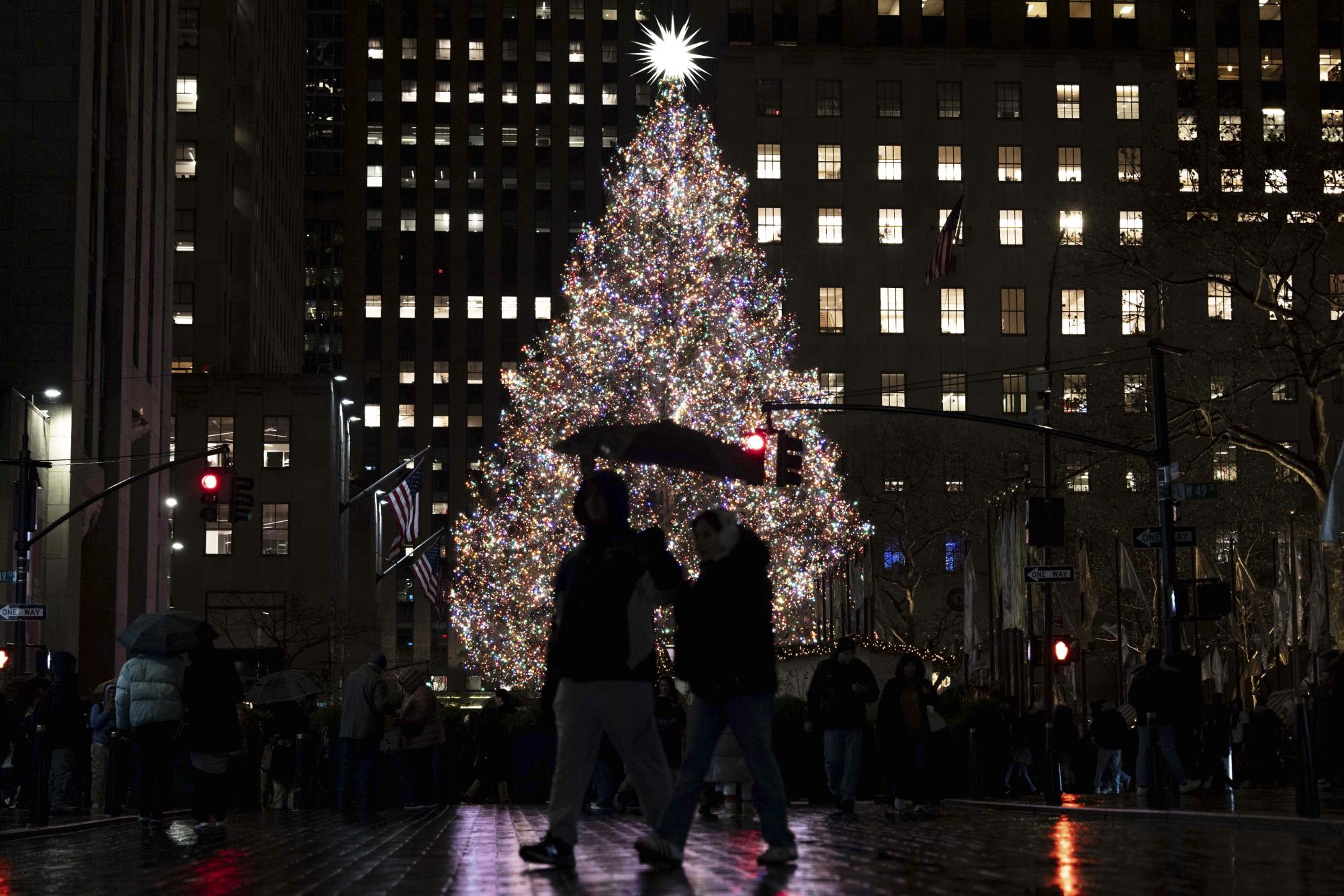 People walk past the Rockefeller Center Christmas tree, Wednesday, Dec. 10, 2025, in New York. (AP Photo/Yuki Iwamura)